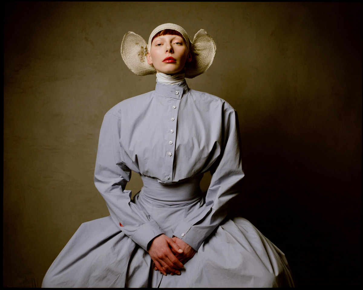 Portrait d’une femme en tenue blanche structurée, lumière douce et fond velouté, symbolisant la maîtrise technique et la tradition photographique avant l’IA.