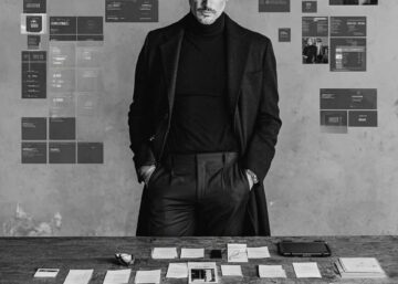 Directeur artistique debout dans un bureau créatif avec moodboard en fond, illustrant l'autorité par un angle de prise de vue frontal et maîtrisé.