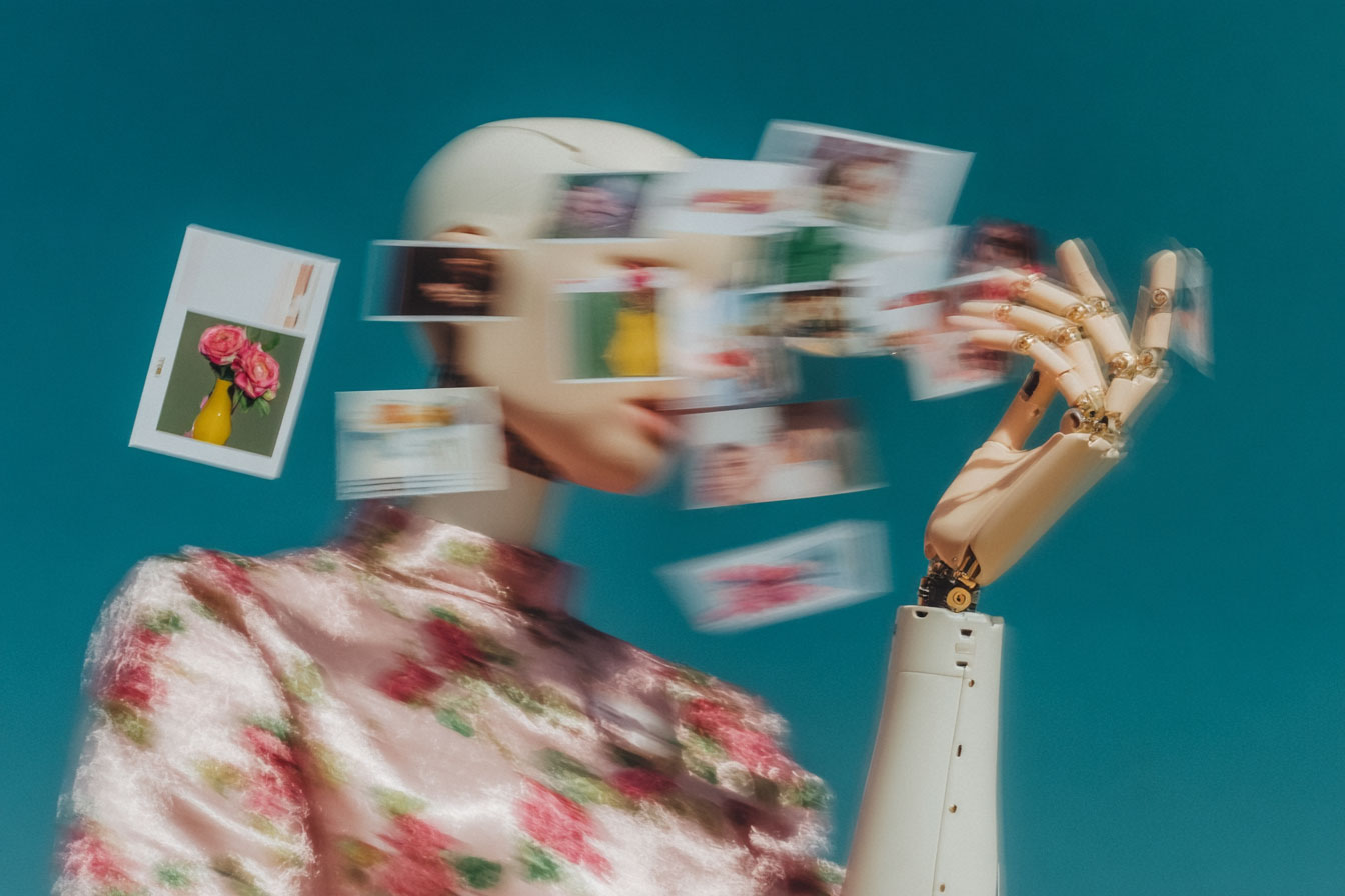Vers les Modèles du Monde (World Models) Bras robotique articulé manipulant un mannequin dont le visage est remplacé par une nuée de photographies volantes, symbolisant l'IA qui tente de se représenter le monde.
