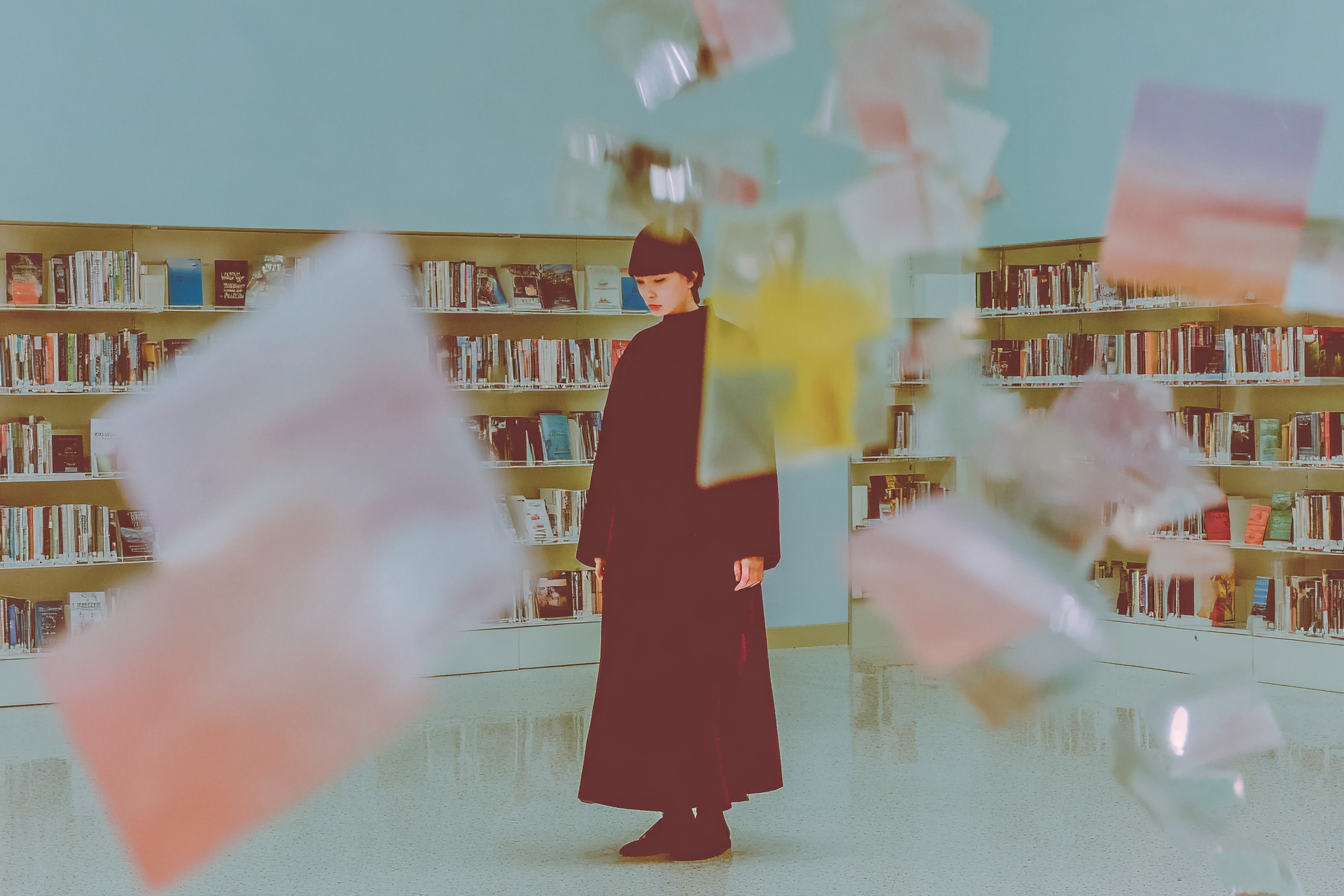 Le Data Wall et la pénurie de données Personne immobile dans une bibliothèque avec des pages de livres volant en éclats au premier plan, représentant l'épuisement imminent des données de haute qualité pour l'IA.